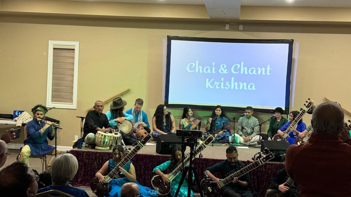Musicians with sitar, tabla and harmonium performing at Chai and Chant — Krishna, with the audience seated around them